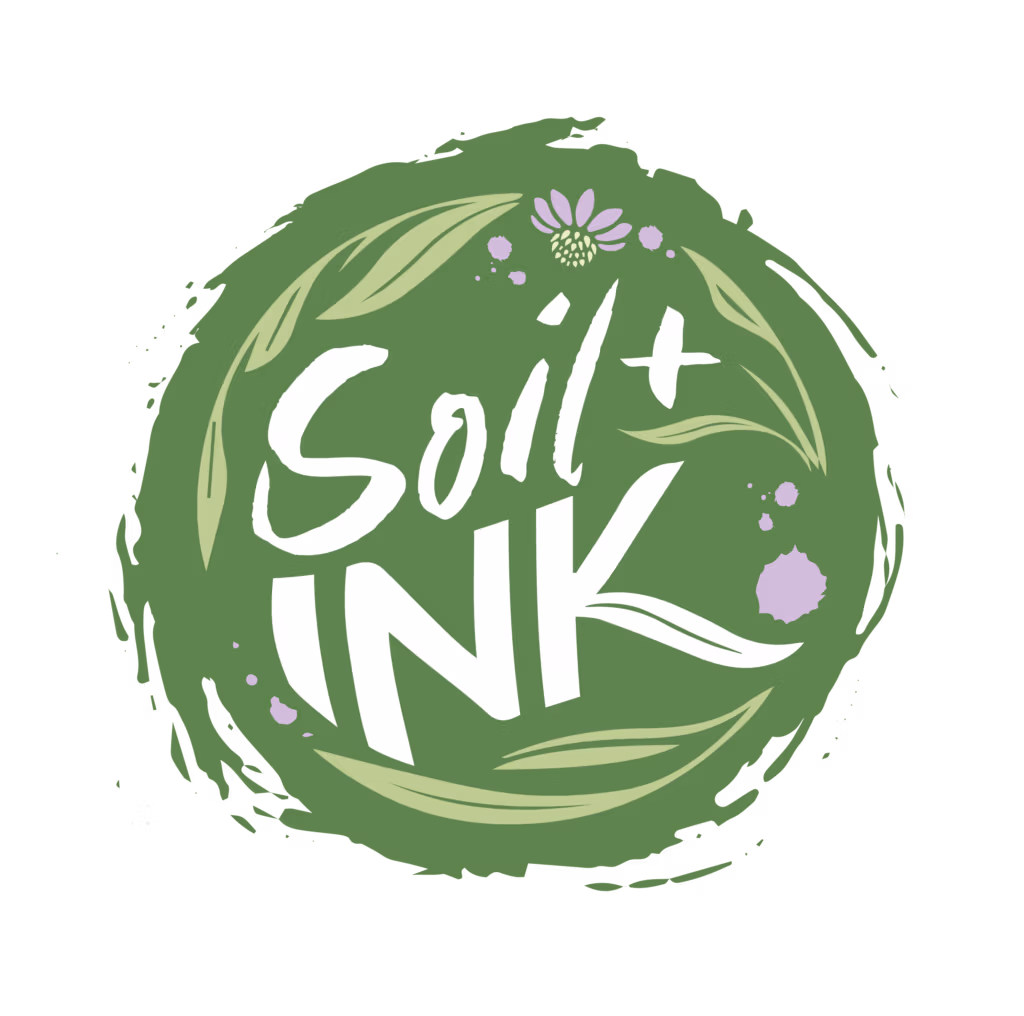 Green circular badge with white decorative script text and a small lavender flower embellishment on a dark background.